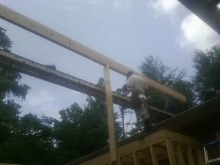 Carpenter setting a ridge beam over a new addition frame — Ice Dam Removal by Roofing Brothers in Sasser
