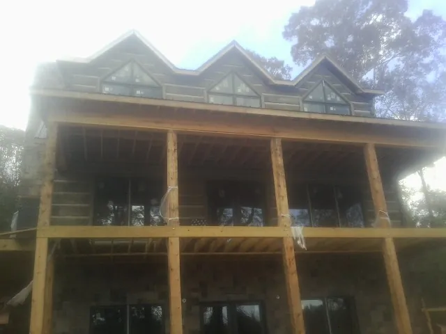 Dormers and porch framing on a large log home under construction — Roof Coating work by our crew in Sasser