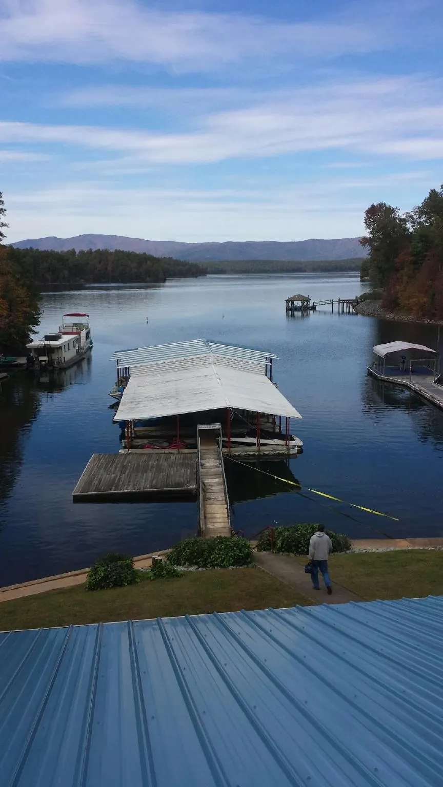View across a lake from a newly installed blue metal roof in Sasser