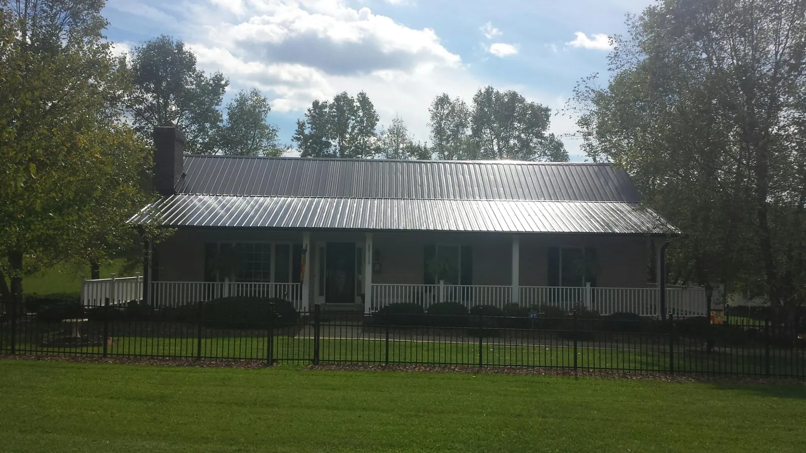 Gray metal roof on a brick ranch with a full width front porch — Gutter Guard Installation work by our crew in Sasser