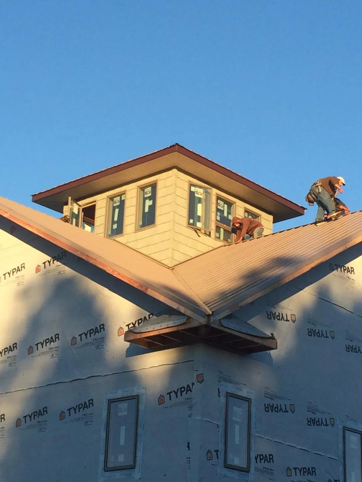 Roofers working around a rooftop cupola on a new metal roof at sunset — Roof Waterproofing in Sasser by Roofing Brothers